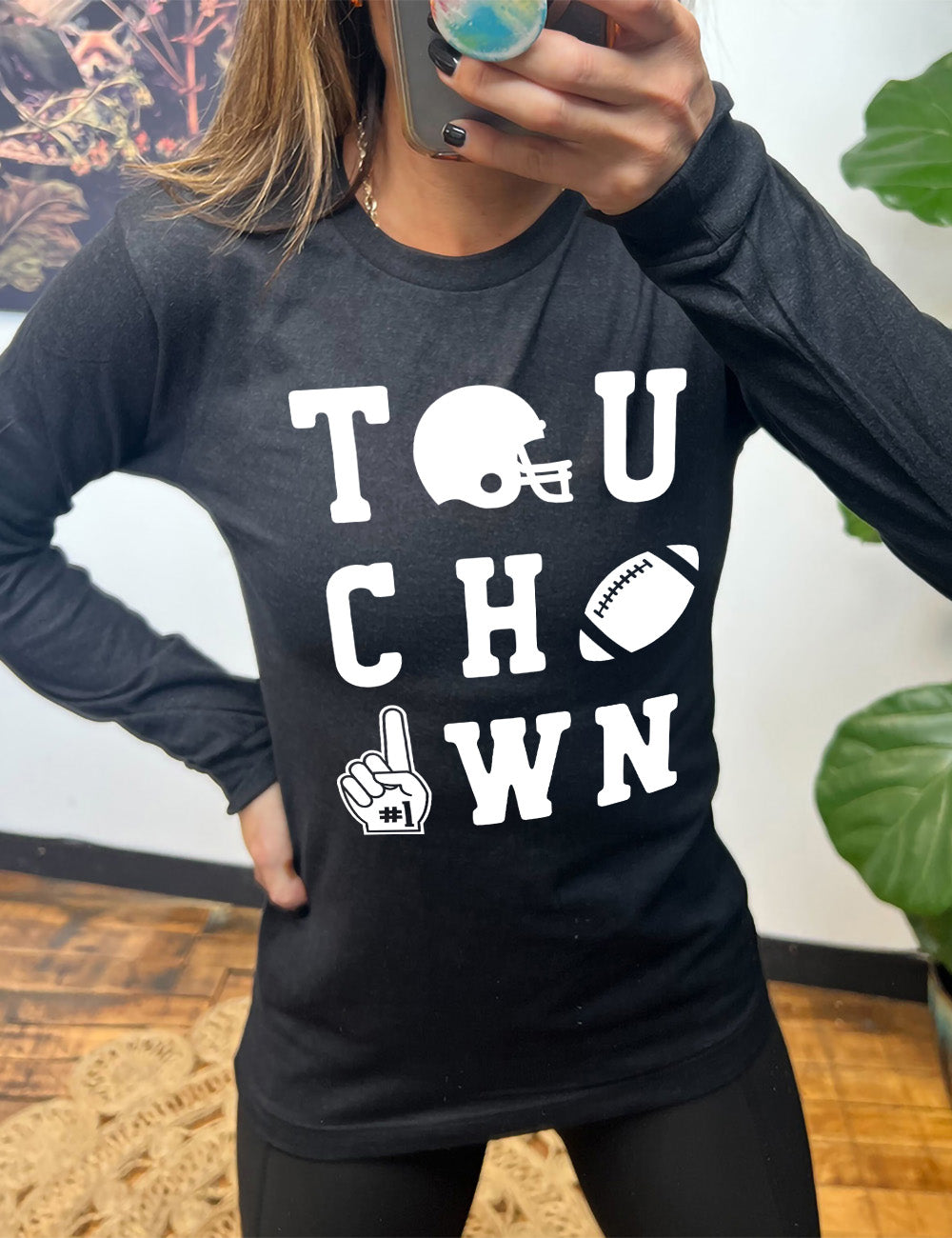 heather black long sleeve tee with the word "touchdown" spelled out over three rows, and with the first "o" being a football helmet, the "d" being a football, and the last "o" being a foam finger with #1 on it