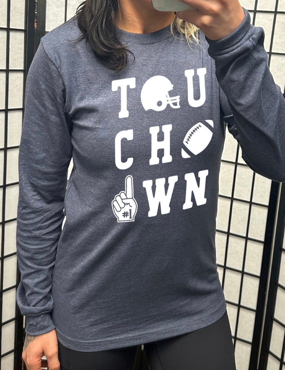 heather navy long sleeve tee with the word "touchdown" spelled out over three rows, and with the first "o" being a football helmet, the "d" being a football, and the last "o" being a foam finger with #1 on it