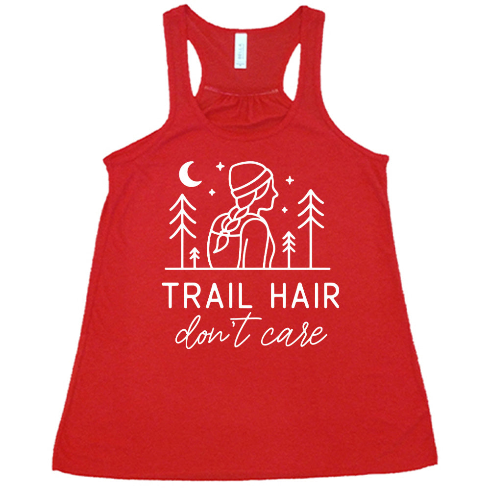 red flowy tank with the words "trail hair don't care" on it, under the line art graphic of a woman with a hat and braided hair, the moon and stars, and four trees