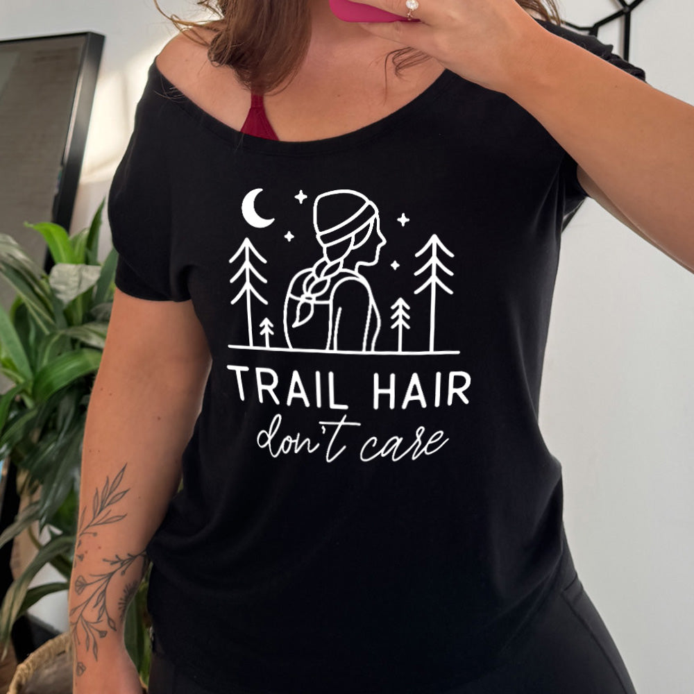 black slouchy tee with the words "trail hair don't care" on it, under the line art graphic of a woman with a hat and braided hair, the moon and stars, and four trees