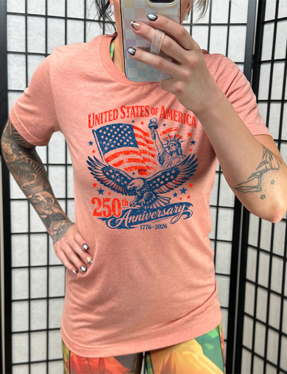 sunset unisex tee with the graphic of the eagle, wings spread, the statue of liberty, and an American flag, and lots of little stars, and the words saying "United Stated of America 250th Anniversary 1776-2026"
