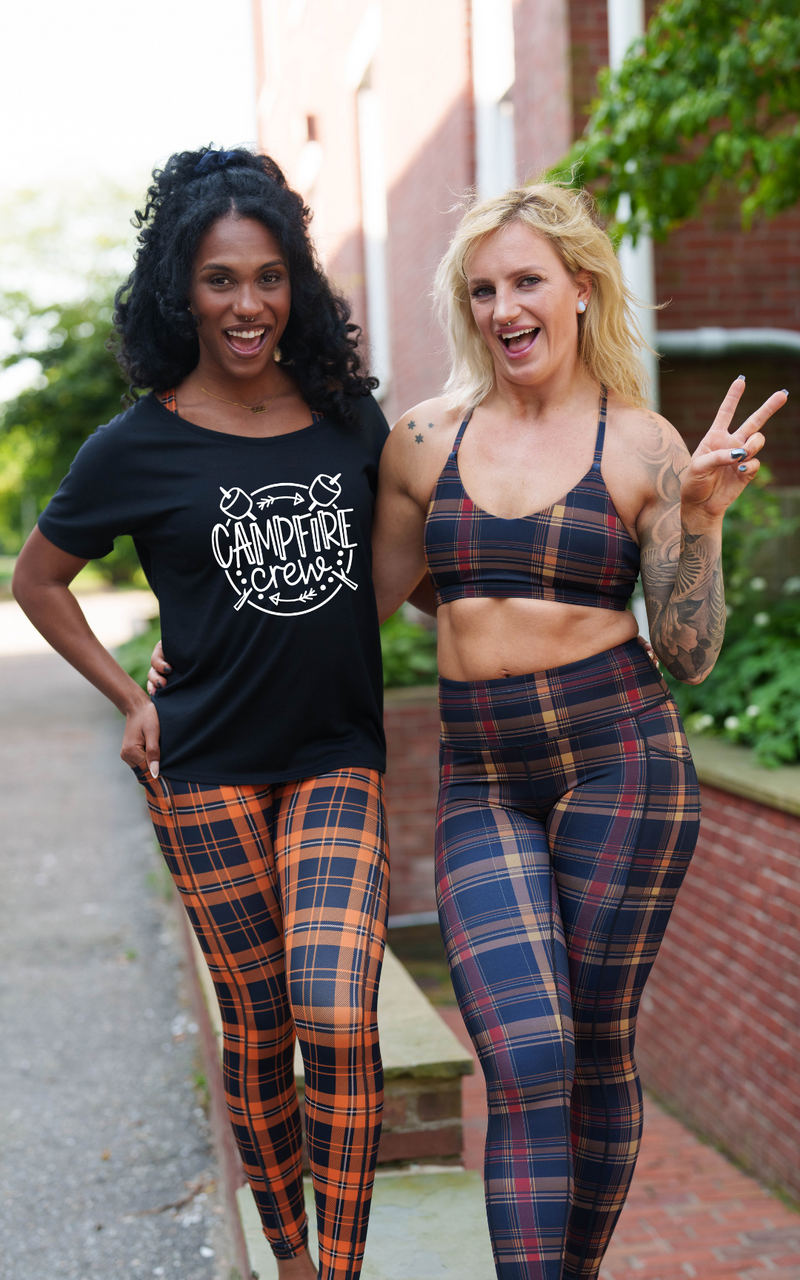 Two women modeling matching plaid activewear and a graphic t-shirt outdoors on a brick path.