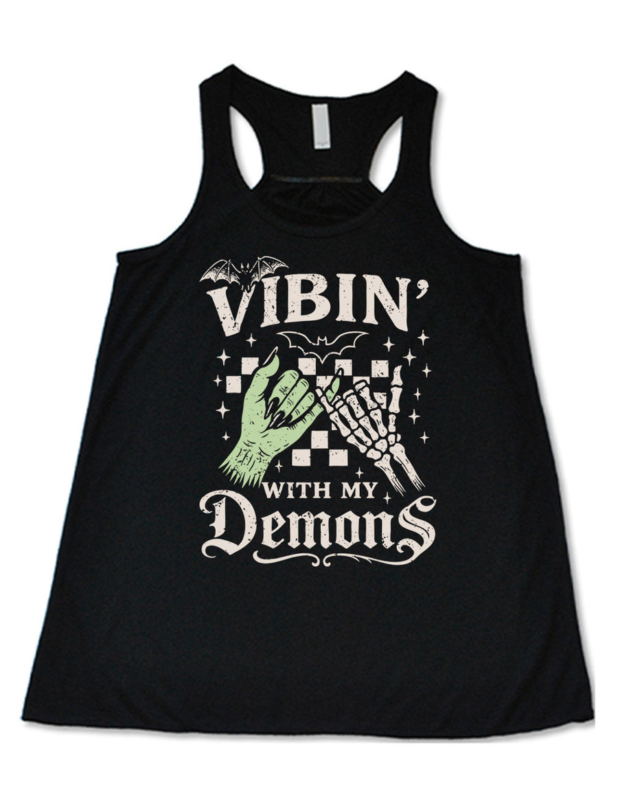 black flowy racerback tank with words saying "Vibin' with my Demons", around the graphic of the hands of a zombie and a skeleton doing a pinky promise, in front of a checkered background, and one line-drawn bat and one detailed bat on top, and scattered stars