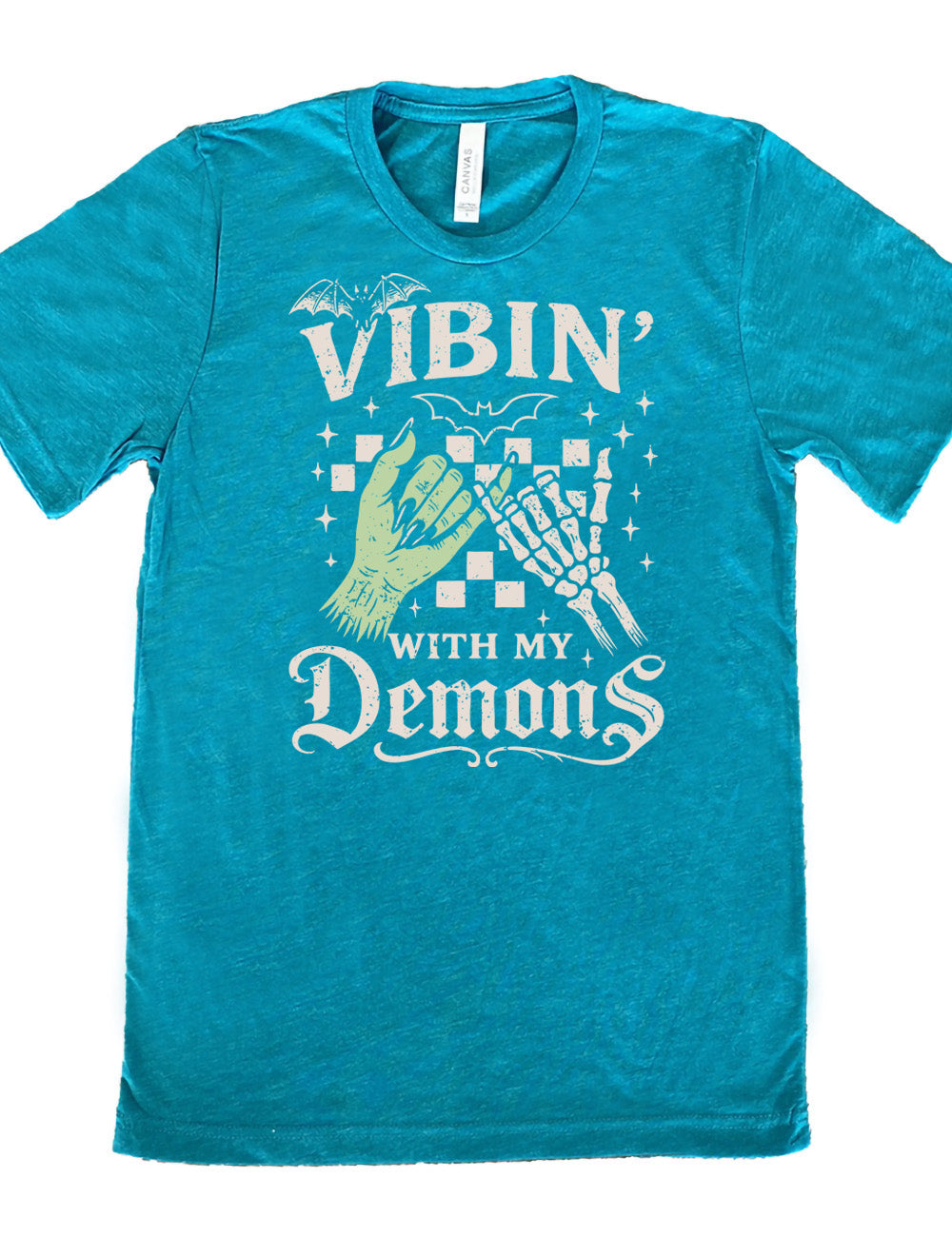 teal unisex tee with words saying "Vibin' with my Demons", around the graphic of the hands of a zombie and a skeleton doing a pinky promise, in front of a checkered background, and one line-drawn bat and one detailed bat on top, and scattered stars