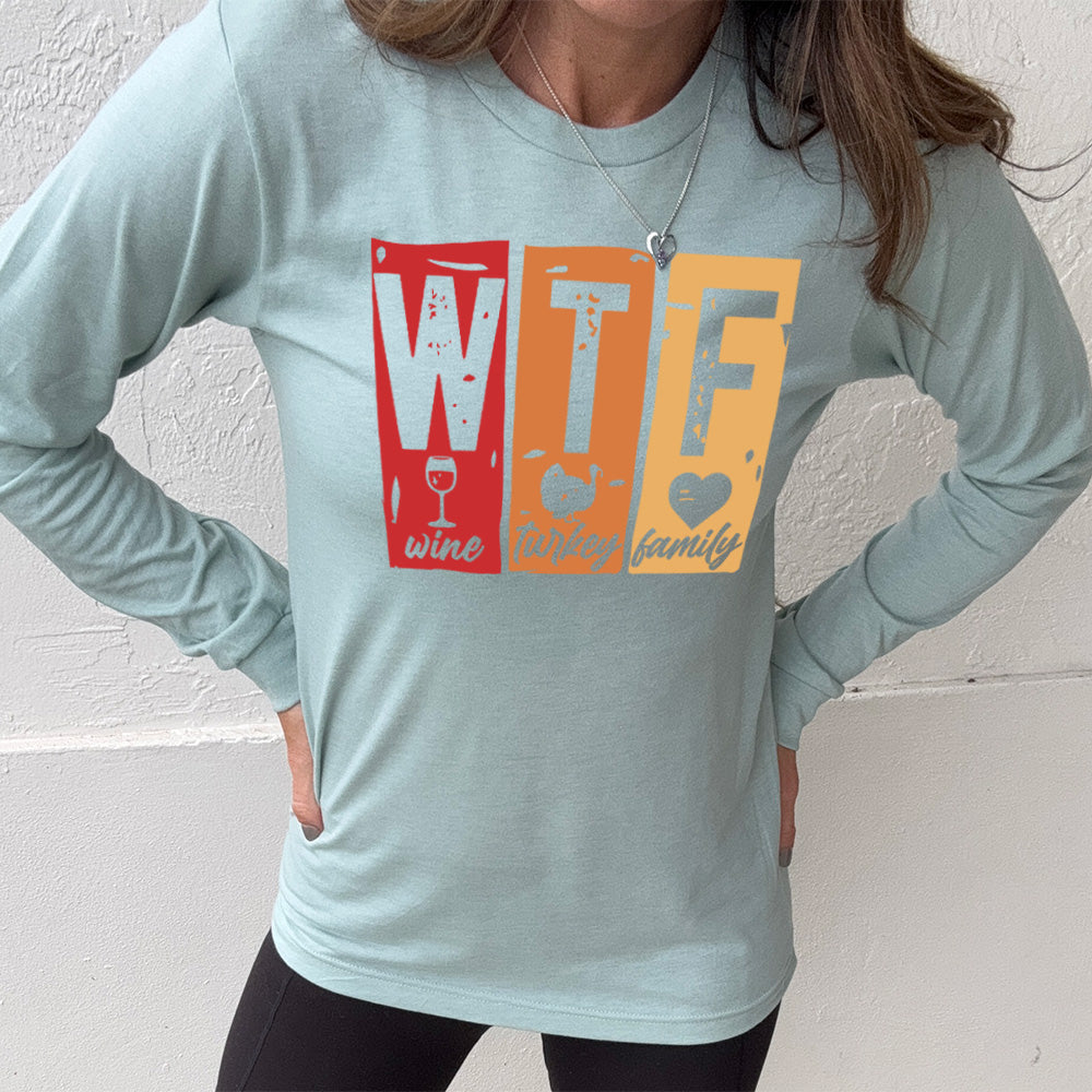 heather dusty blue long sleeve shirt with a graphic on it that says "WTF" and under the "W" there's a graphic of a wine glass and the word "wine"; under "T" there's a graphic of a turkey and the word "turkey"; under F there's a graphic of a heart and the word "family"