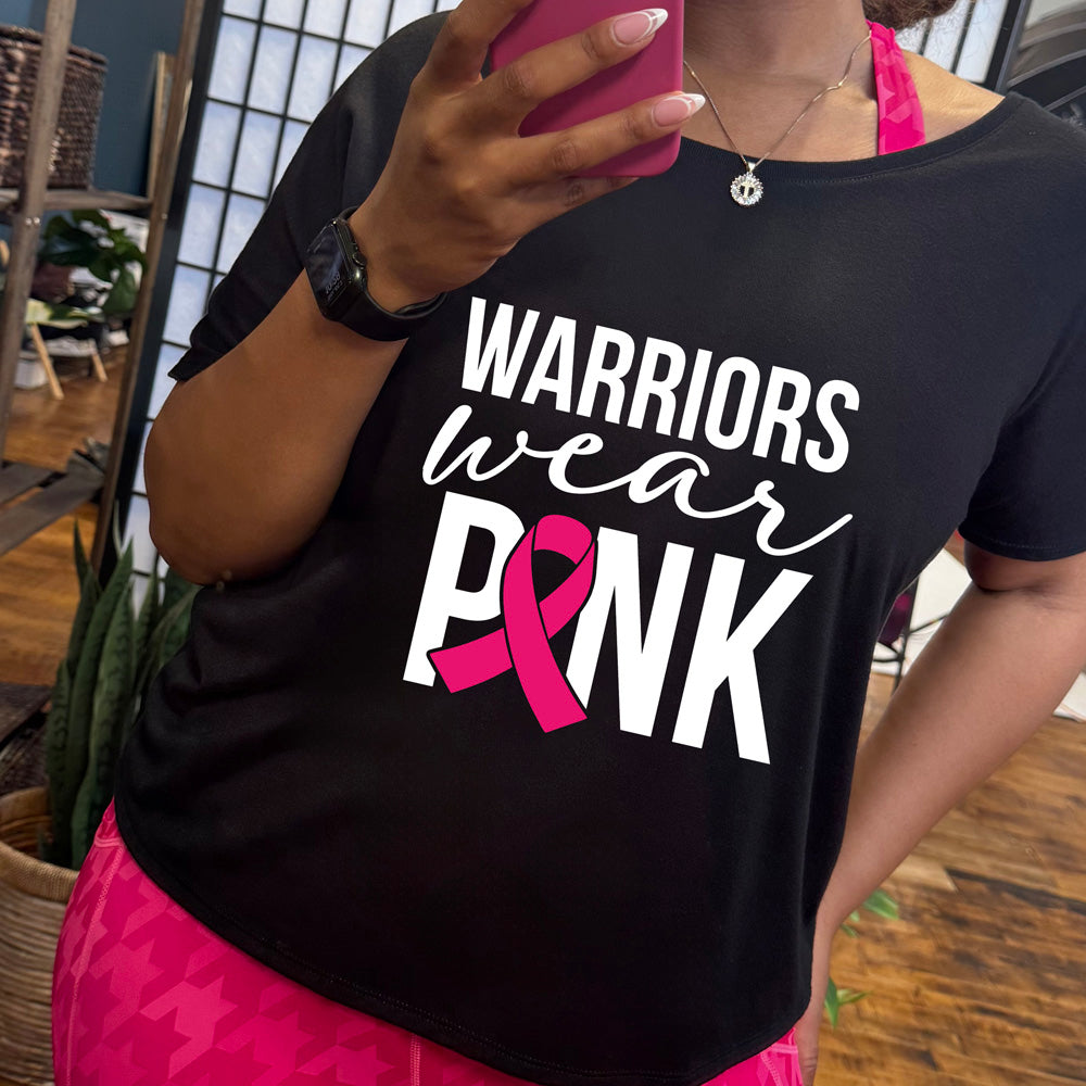 Person wearing a black t-shirt with 'Warriors wear Pink' design, taking a mirror selfie