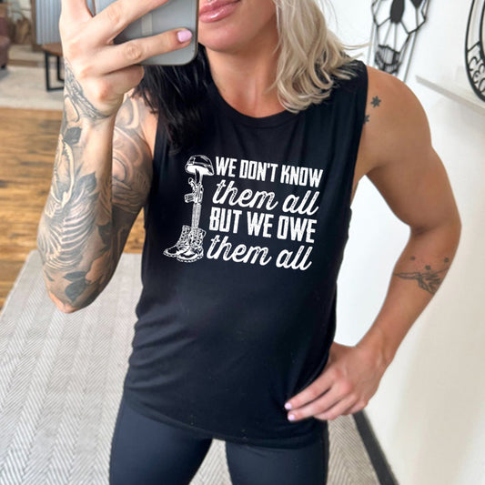 model wearing the black "We Don't Know Them All But We Owe Them All" Muscle Tank