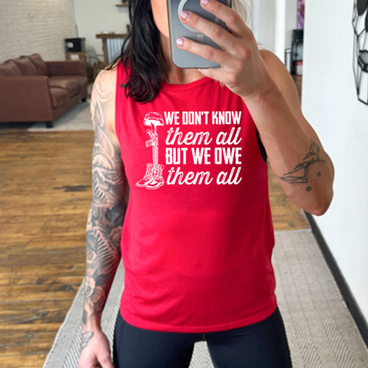 model wearing the red "We Don't Know Them All But We Owe Them All" Muscle Tank