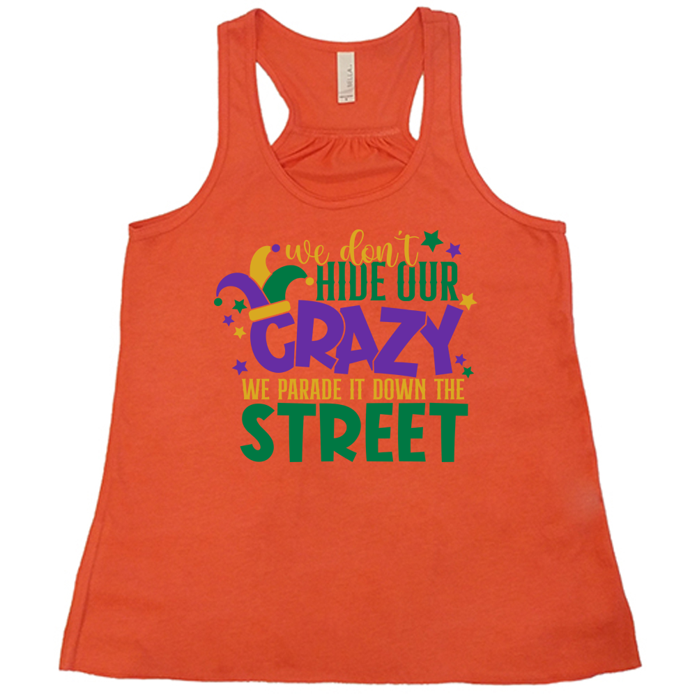 coral flowy tank with the words "we don't hide our crazy we parade it down the street" on it with a joker hat on the letter "c" and a few little stars scattered around