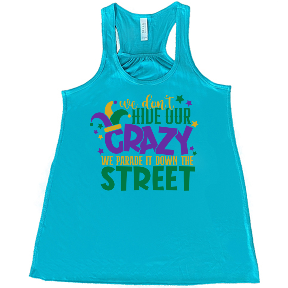 teal flowy tank with the words "we don't hide our crazy we parade it down the street" on it with a joker hat on the letter "c" and a few little stars scattered around
