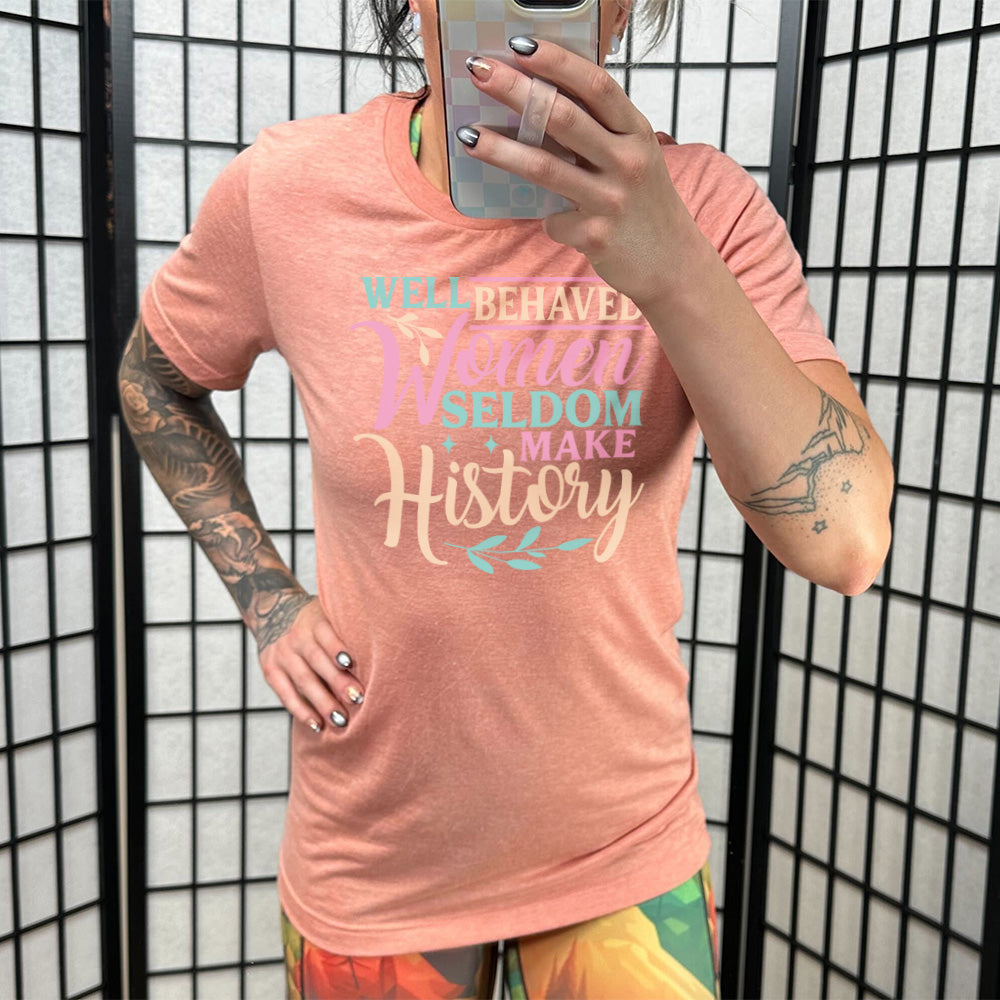 Sunset unisex tee, with wording Well Behaved Women Seldom Make History, with varying font color, with two branches and two stars.