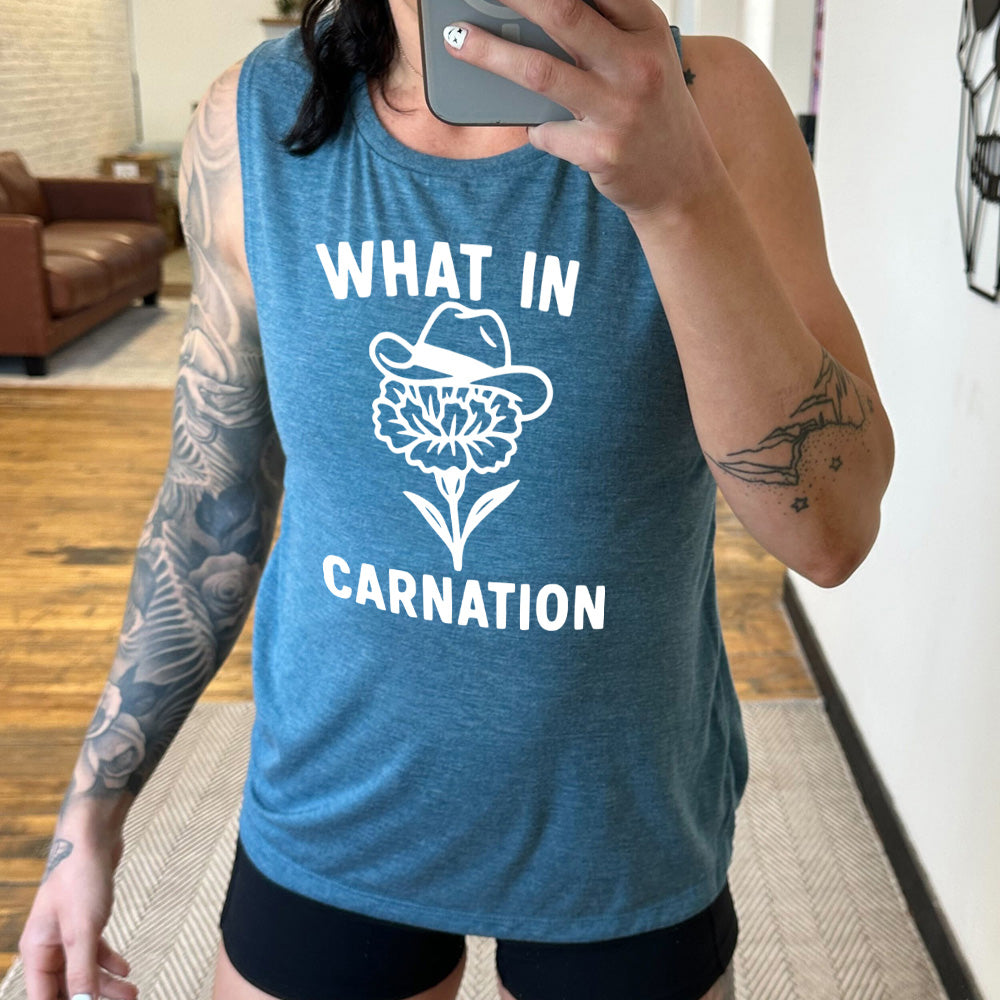deep teal muscle tank with the words "What in carnation" on it, around the graphic of a carnation, wearing a cowboy hat