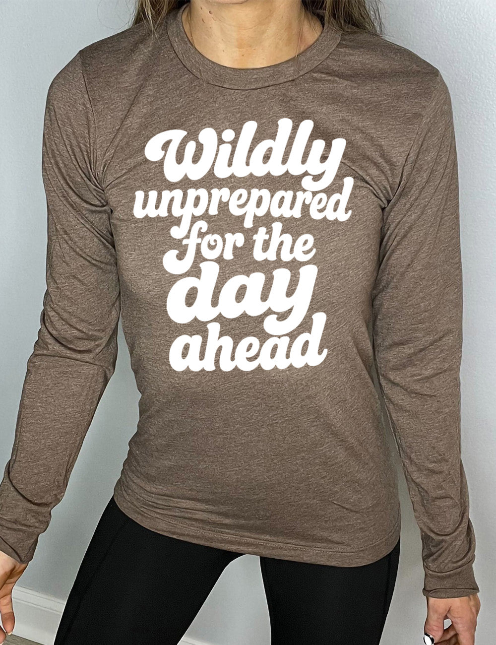 heather brown long sleeve tee with words on it saying "Wildly unprepared for the day ahead"