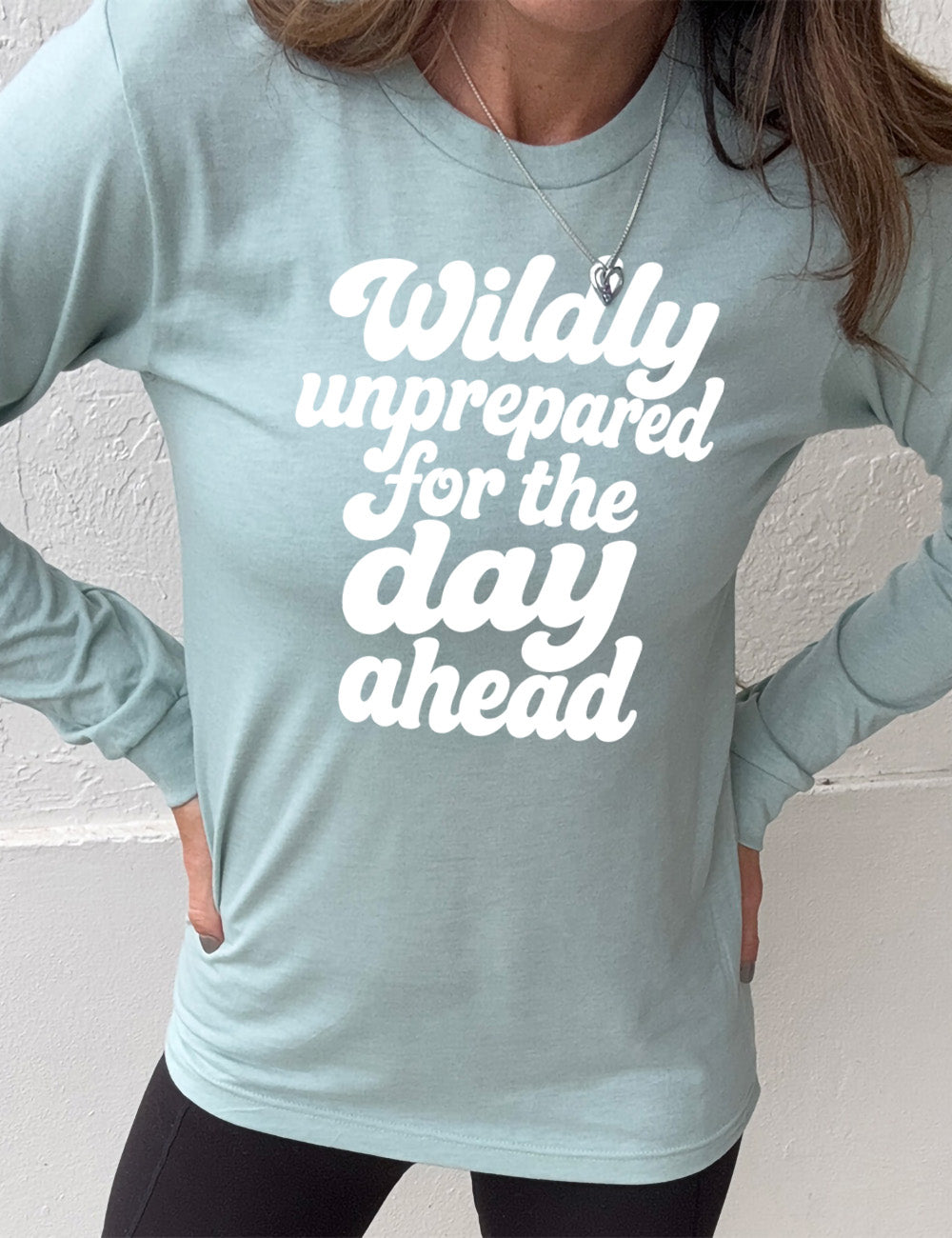 heather dusty blue long sleeve tee with words on it saying "Wildly unprepared for the day ahead"