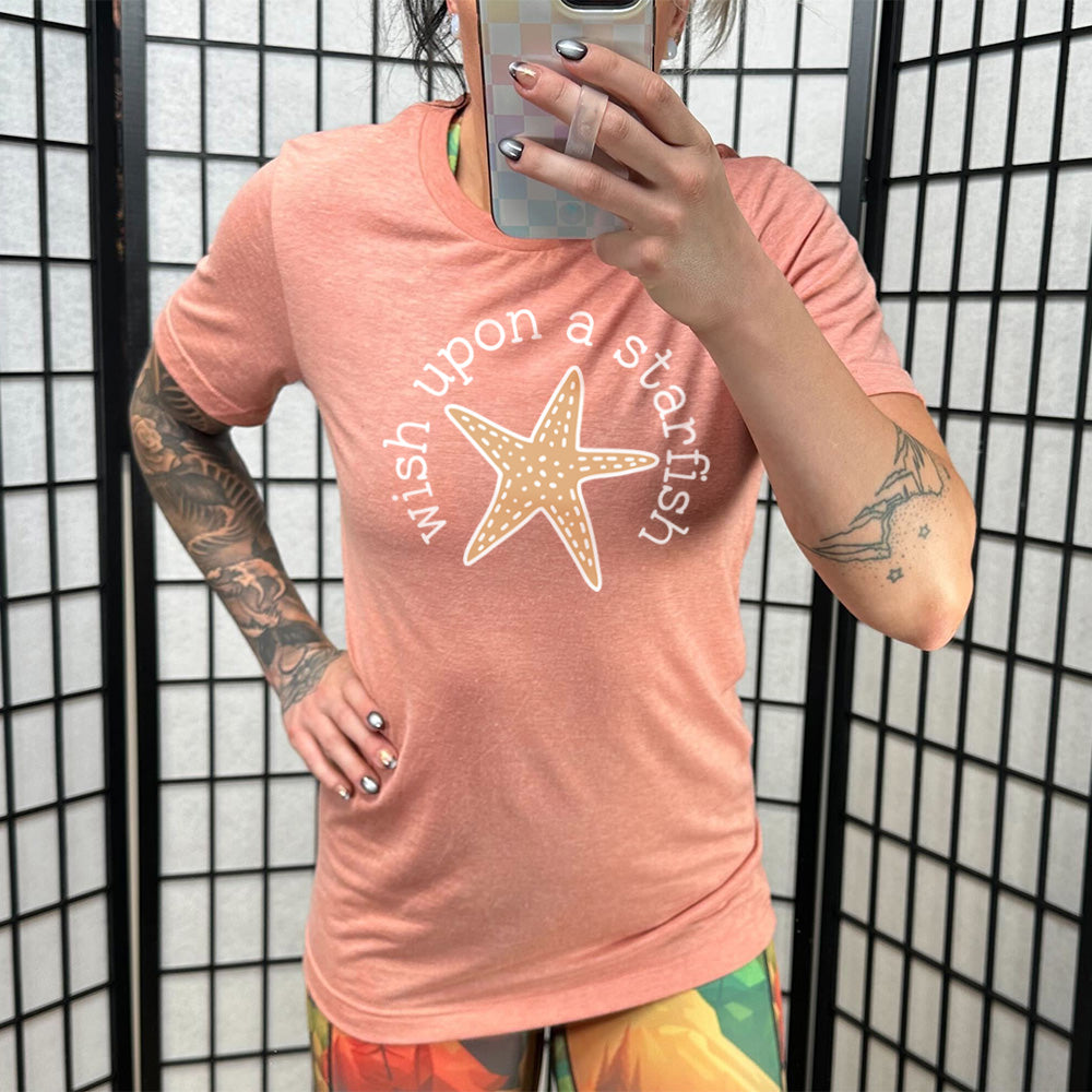 sunset unisex tee with the graphic of a starfish, and the words arched around it saying "wish upon a starfish"