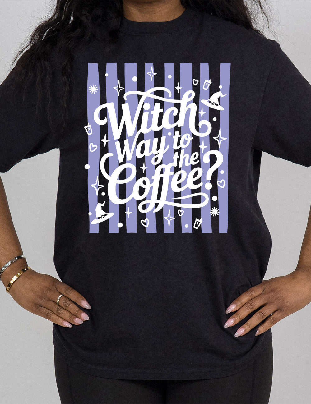 black modern tee with the words "witch way to the coffee?" on it, over a striped background, surrounded by little graphics including stars, hearts, witch hats, coffee cups, dots, and suns