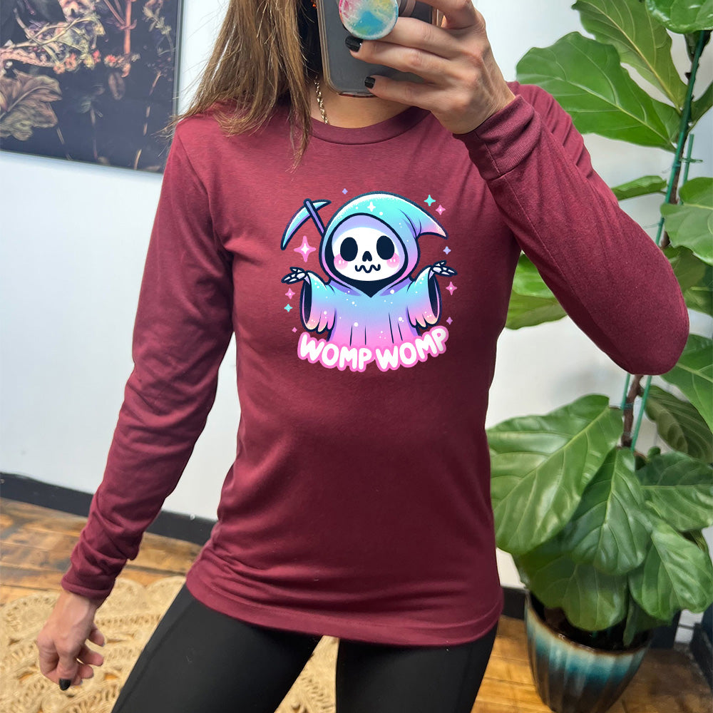 heather cardinal long sleeve shirt with the text "Womp Womp" on it, with the cartoon graphic of a sparkly-robed grim reaper, skeletal hands raised in question, surrounded by sparkly little stars