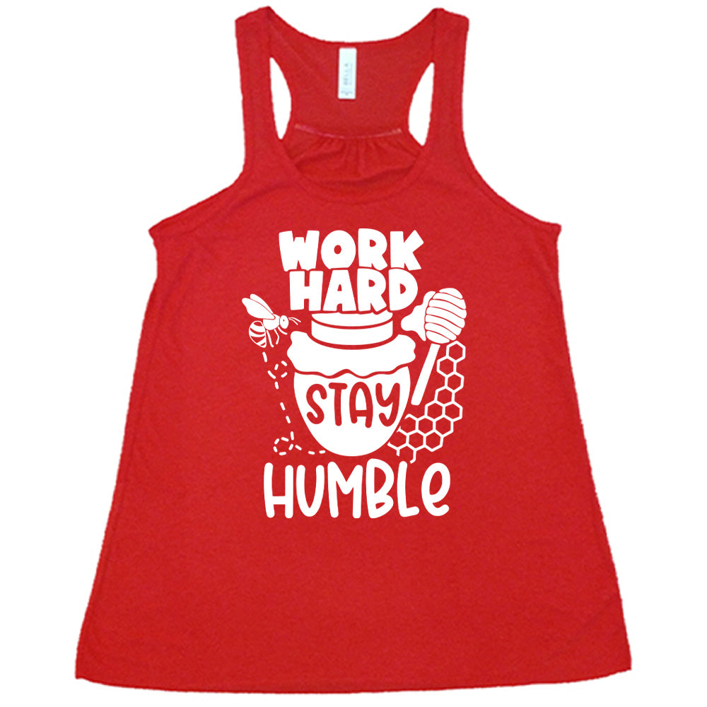 red flowy racerback tank with the words "work hard stay humble" on it, with the word "stay" on the graphic of a honeypot, and a bee flying around the pot's left, and some honeycomb and a honey spoon on its right