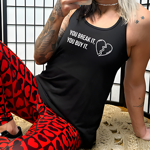 model wearing a black tank top with the saying "You Break It You Buy It" on it in white