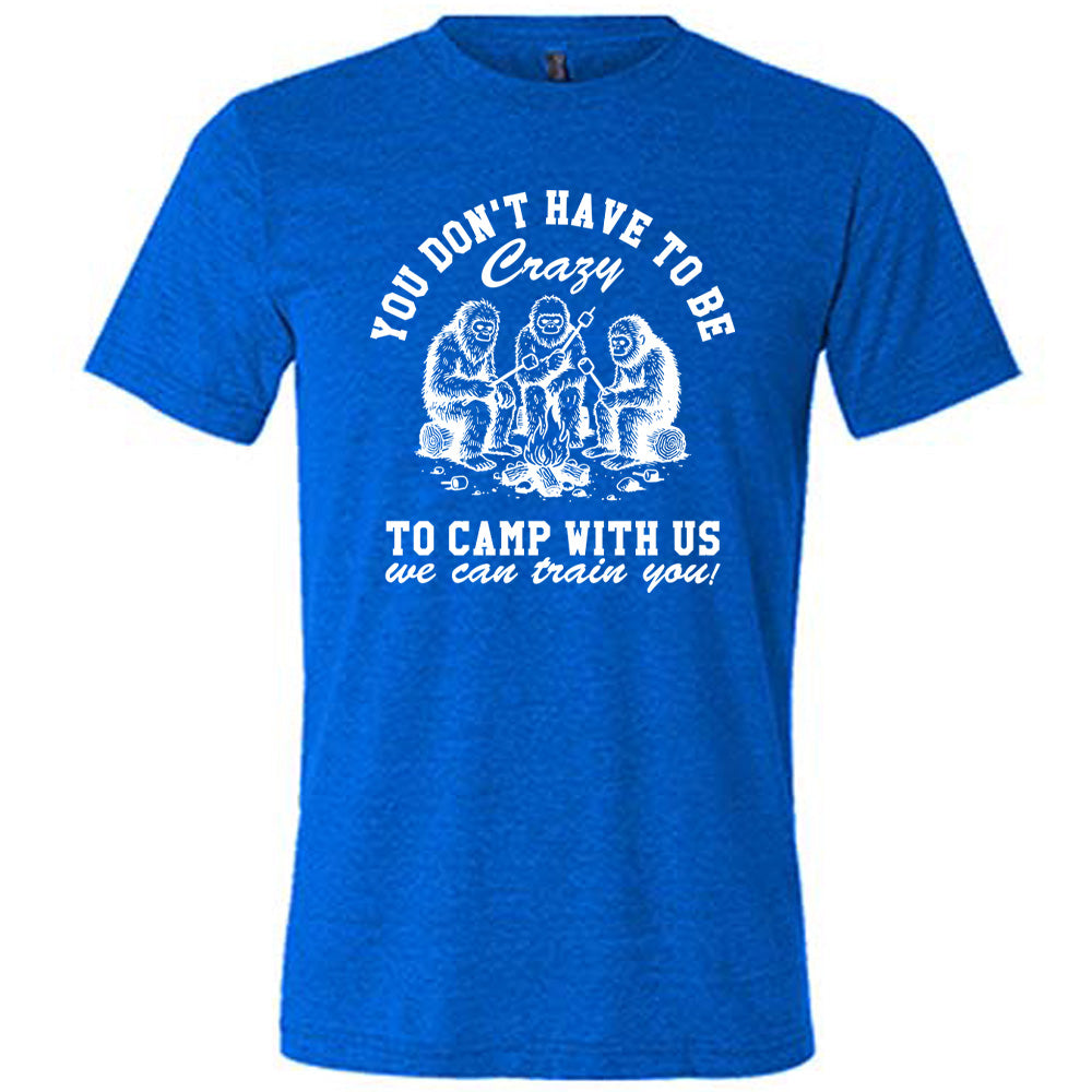 blue unisex tee with the words "you don't have to be crazy to camp with us we can train you!" on it with the graphic of three sasquatches toasting marshmallows over a campfire