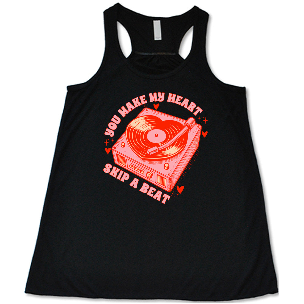 black flowy shirt with the words "you make my heart skip a beat" on it, with the graphics of a record player, with a record shaped like a heart, with a little hearts and stars around each corner of the player