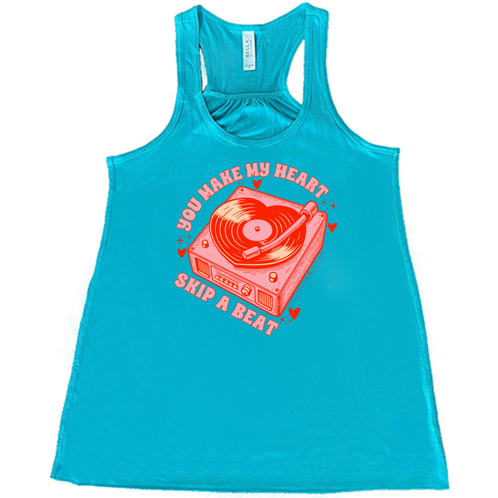 teal flowy shirt with the words "you make my heart skip a beat" on it, with the graphics of a record player, with a record shaped like a heart, with a little hearts and stars around each corner of the player