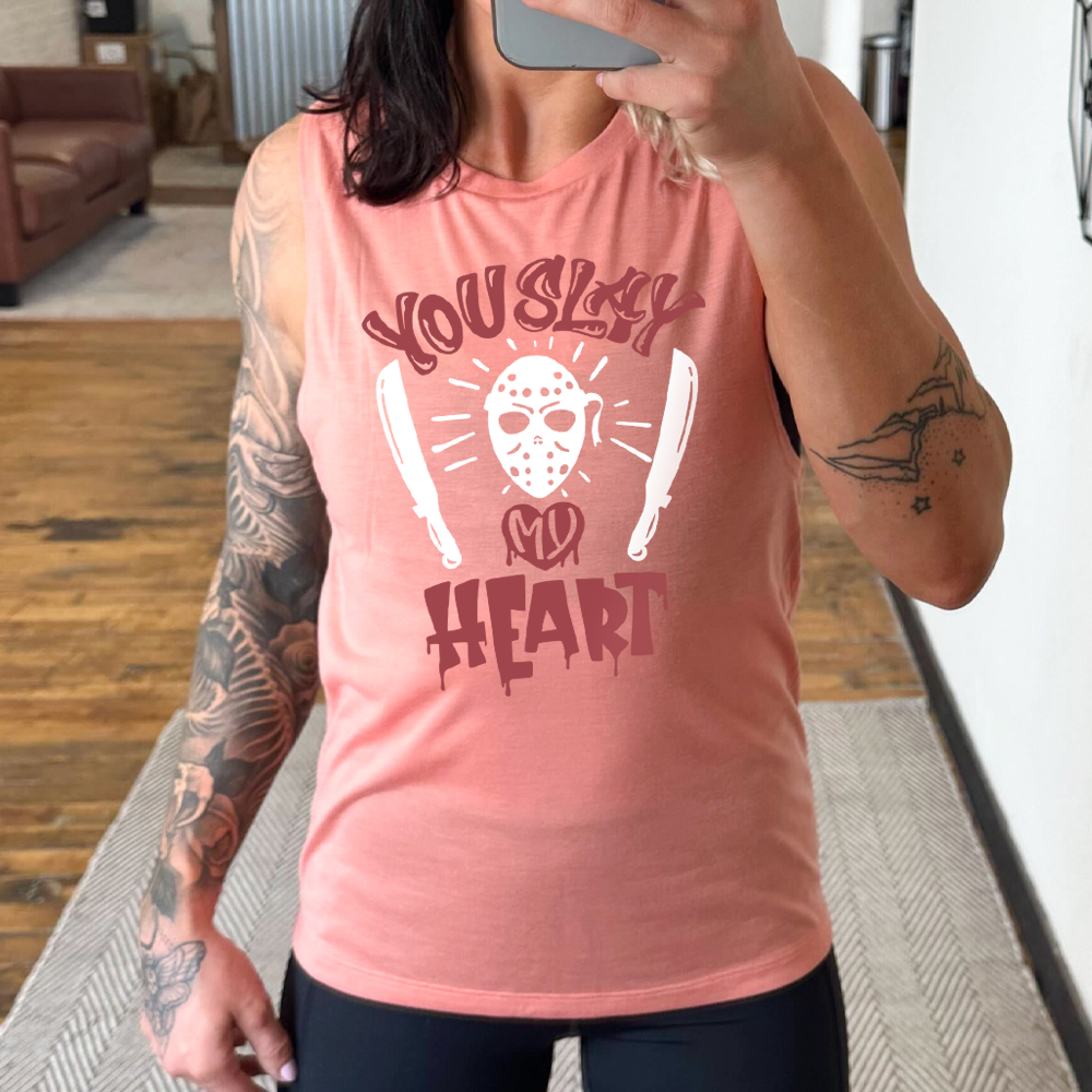 peach muscle tank with the words "you slay my heart" on it in horror movie style writing, with "my' being in a dripping heart, and graphics of the Jason mask from Friday the 13th and two machetes 