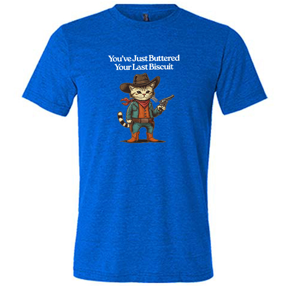 Blue colored shirt with a cowboy cat graphic on it that says "You've Just Buttered Your Last Biscuit"