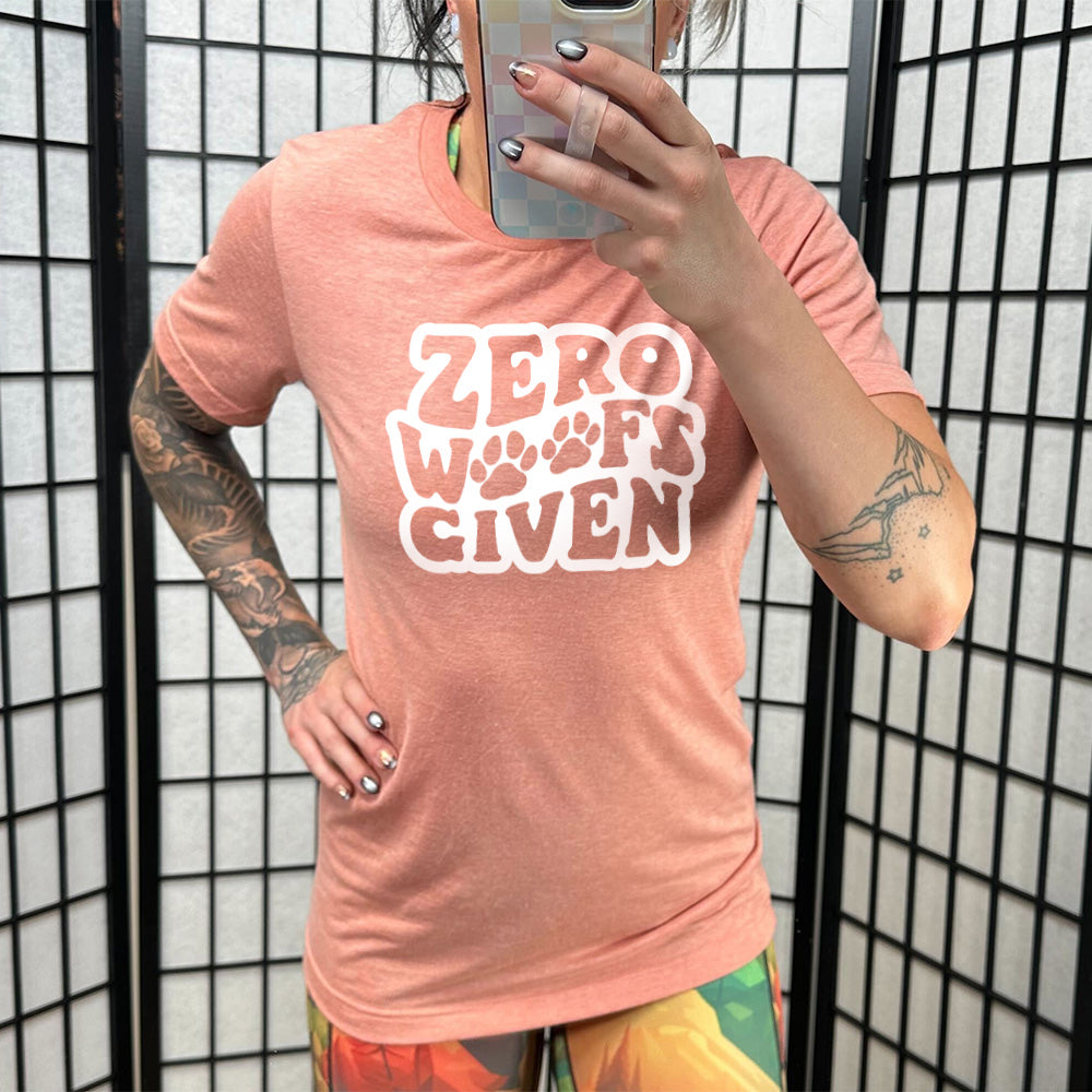Model wearing sunset colored shirt with paw print graphic on it that says "Zero Woofs Given"