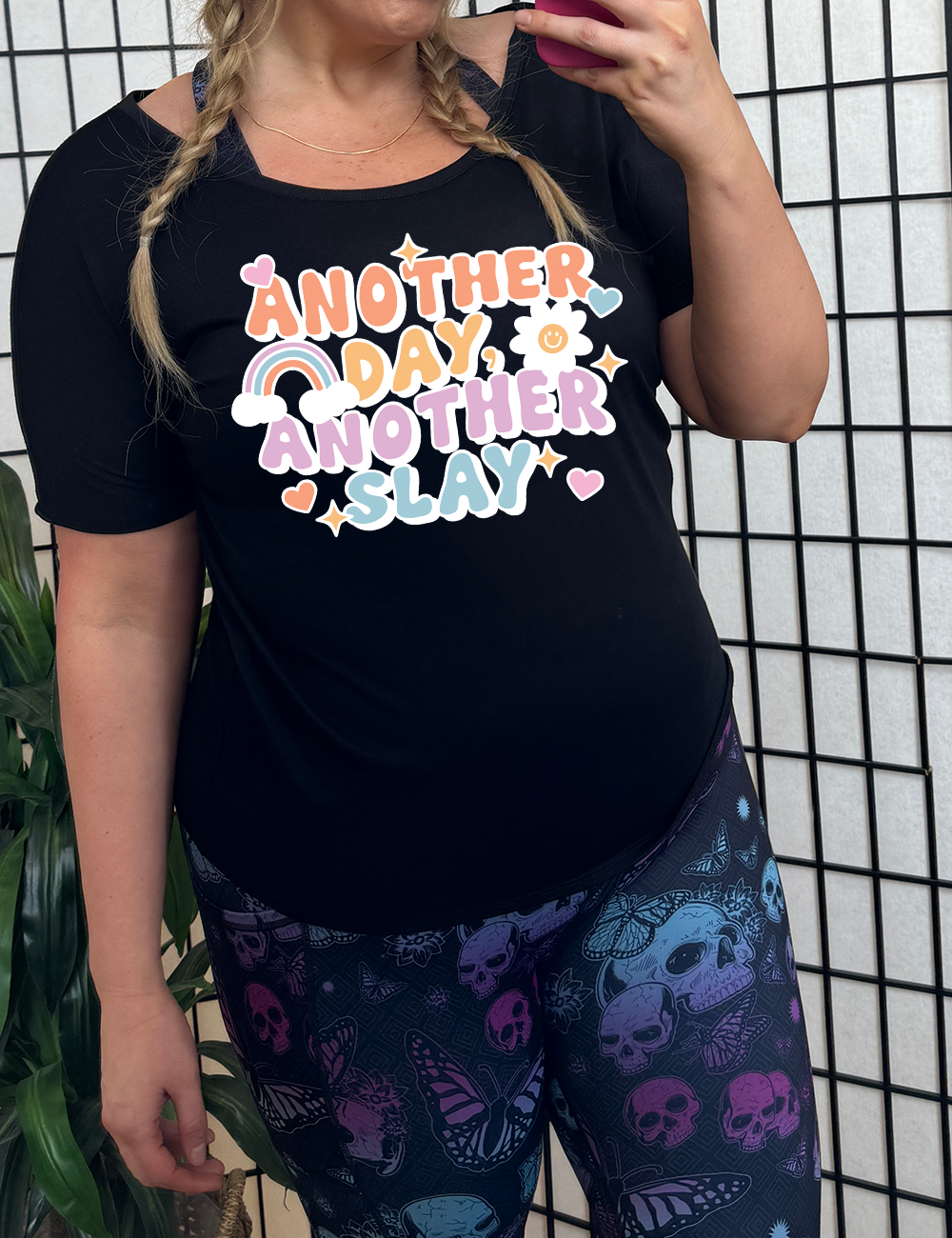 black slouchy tee with the words "another day, another slay" on it, with little graphics of stars, hearts, a sun, and a rainbow