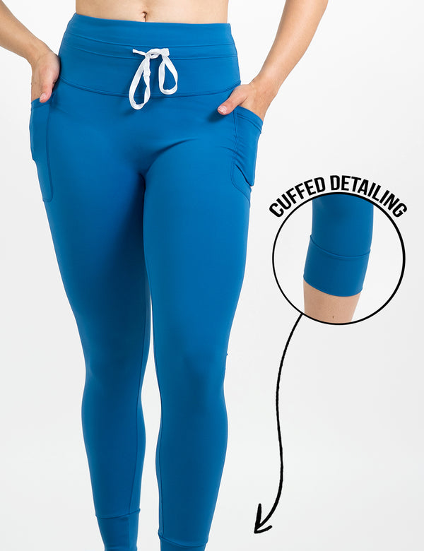 front of the blue omni style leggings with a white draw string against a white background, including a close up of the cuffed detailing