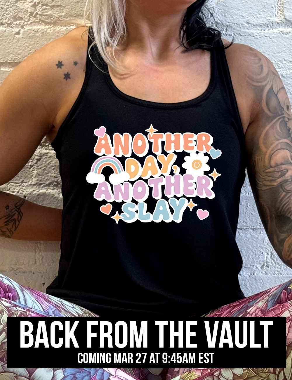 black racerback flowy tank with the words "another day, another slay" on it, with little graphics of stars, hearts, a sun, and a rainbow, coming soon