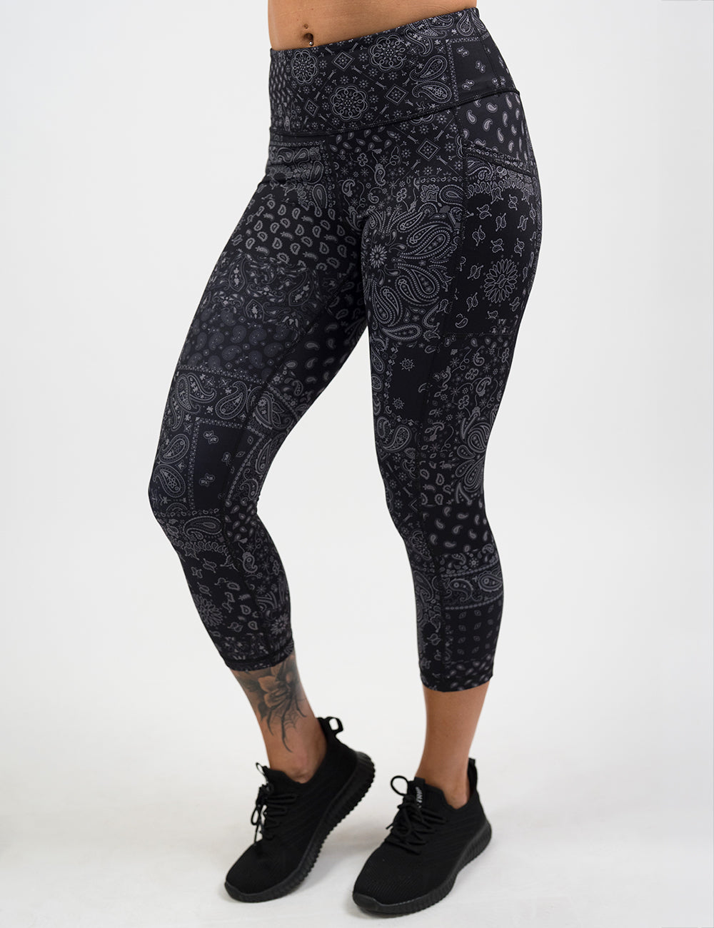 model wearing the capri black paisley patterned leggings against a white background