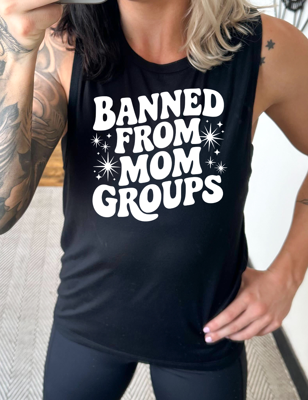 black muscle tank with the words "banned from mom groups" on it, with stars on either side of the words "from mom"