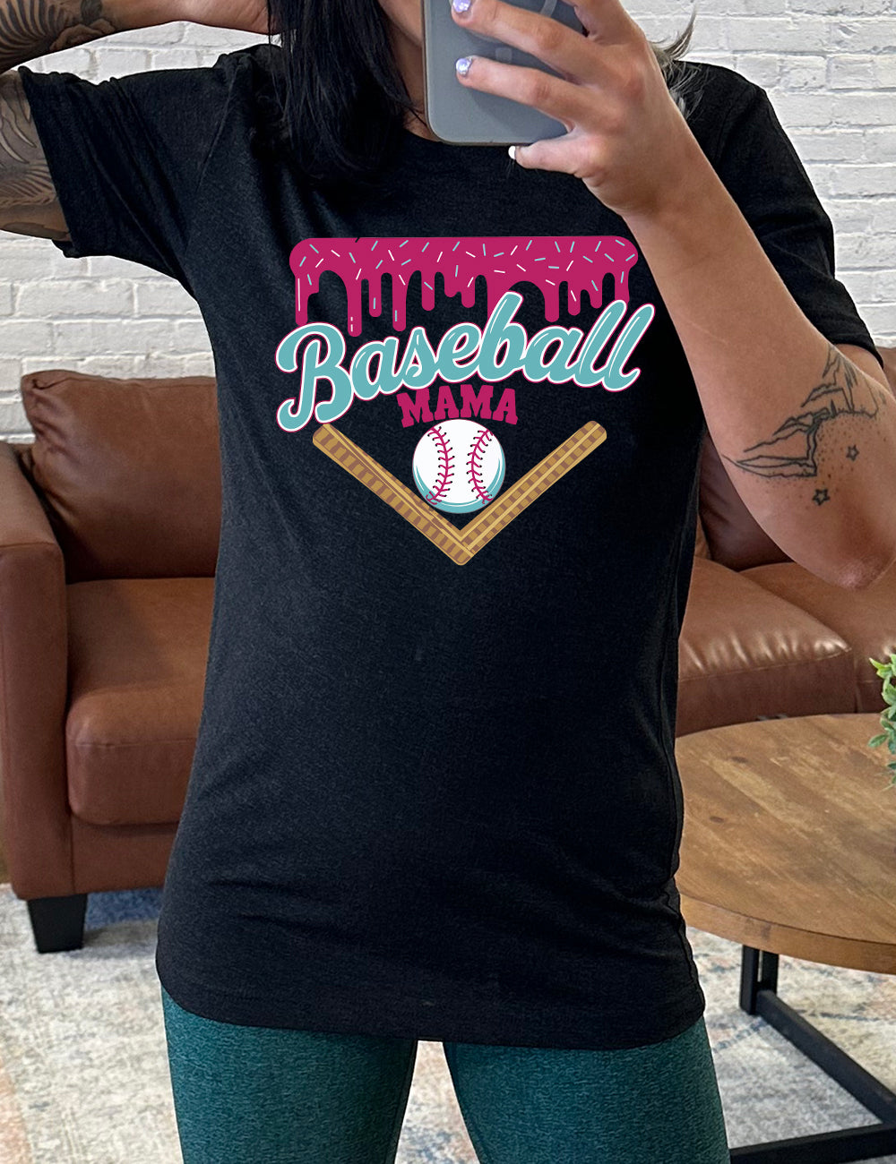 black unisex tee with the words "baseball mama" on it, with a border with sprinkles above the words, dripping down, and a baseball underneath the words, and a border in a V below everything