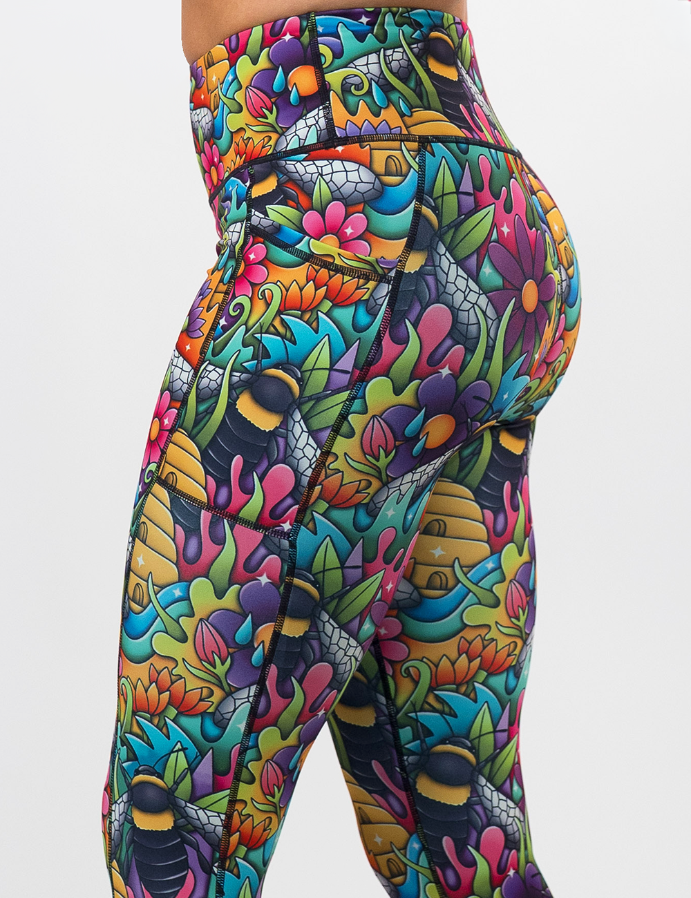 close up of the cartoon bees against bold colorful cartoon flowers pattern leggings against a white background