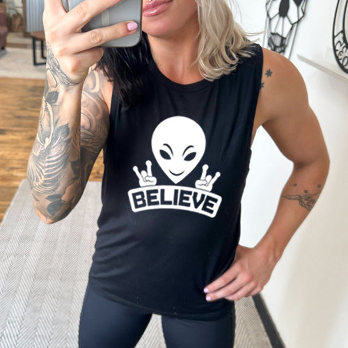 black muscle tank top that has an alien design on it that says "believe"