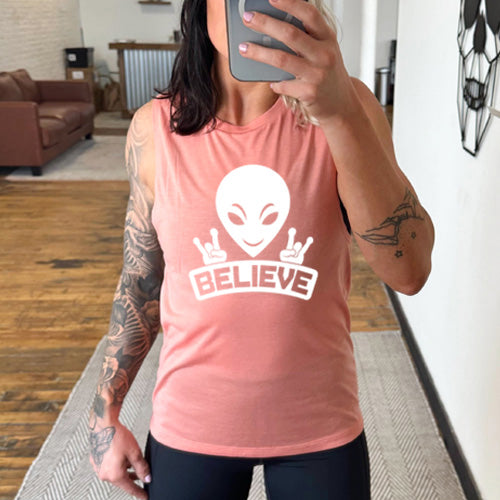 peach muscle tank top that has an alien design on it that says "believe"