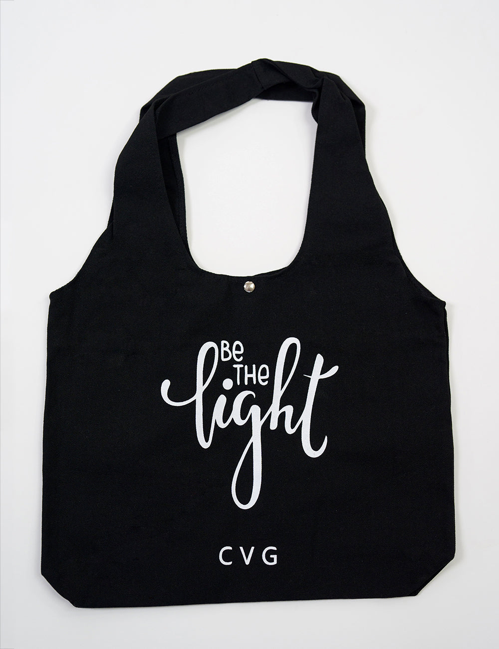 Black tote bag with the CVG logo and the large words "be the light" on it