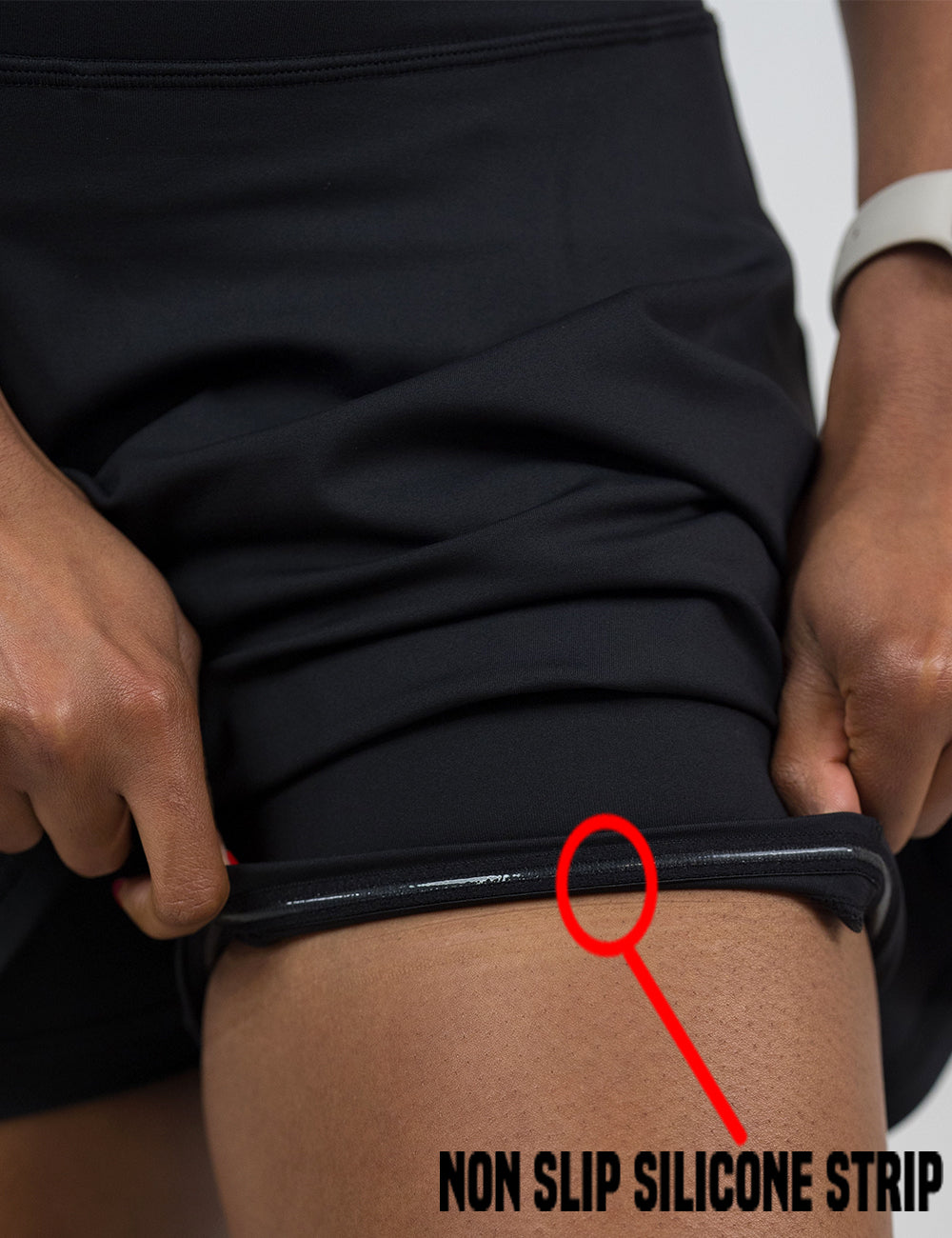 close up of the all black skirt being rolled up to show the non slip silicone strip found in the lining of the under shorts