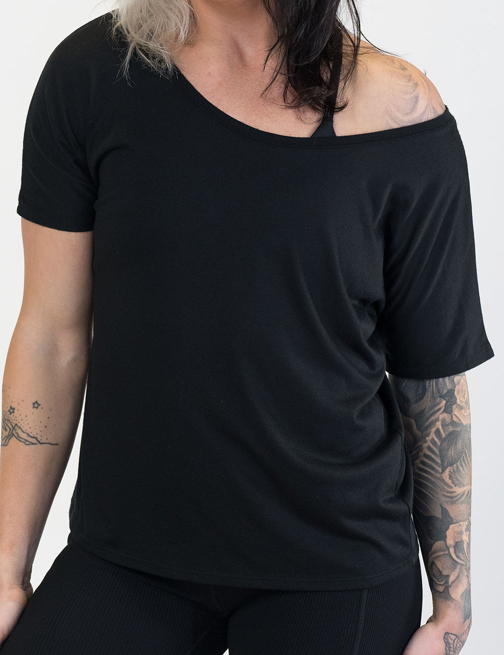 Model wearing a black slouchy tee, that falls off the shoulder.