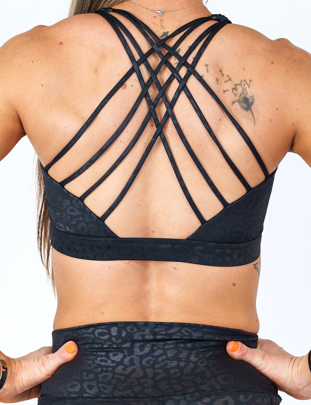 back view of black on black leopard print sports bra with butterfly back strap design