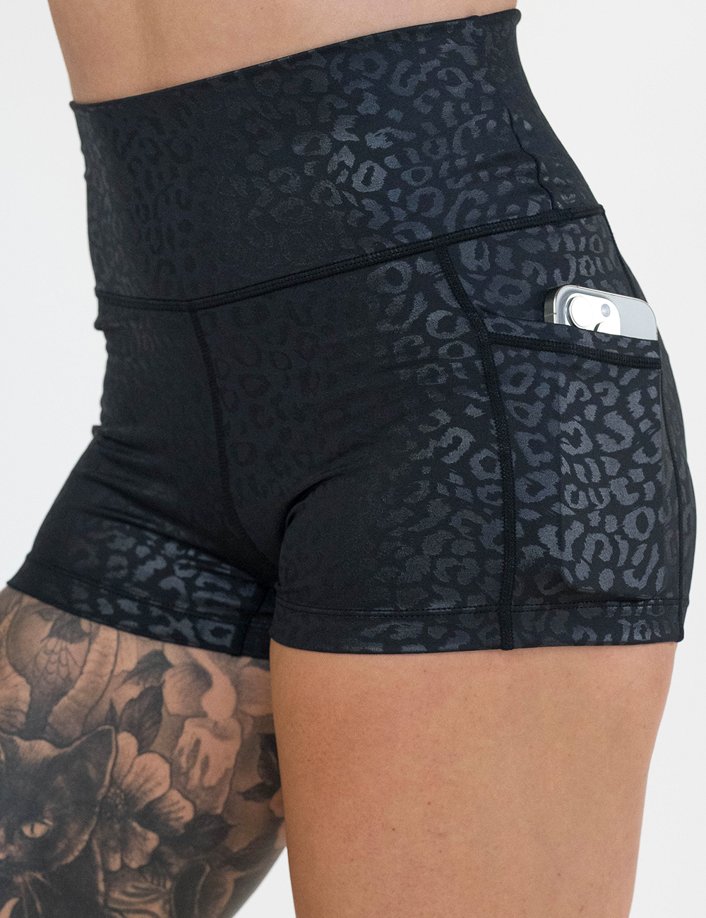 close up of the 2.5 inch black leopard print shorts with a phone in the pocket against a white background