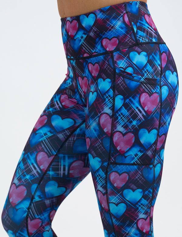 close up of blue and pink hearts pattern against a dark stitched background leggings