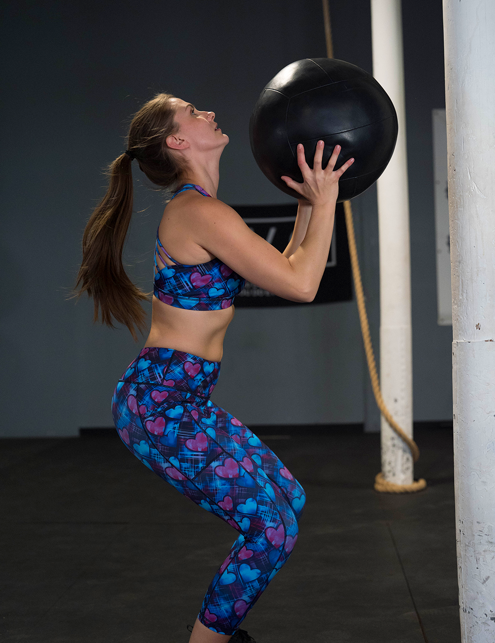 blue and pink hearts pattern against a dark stitched background capri leggings in the gym