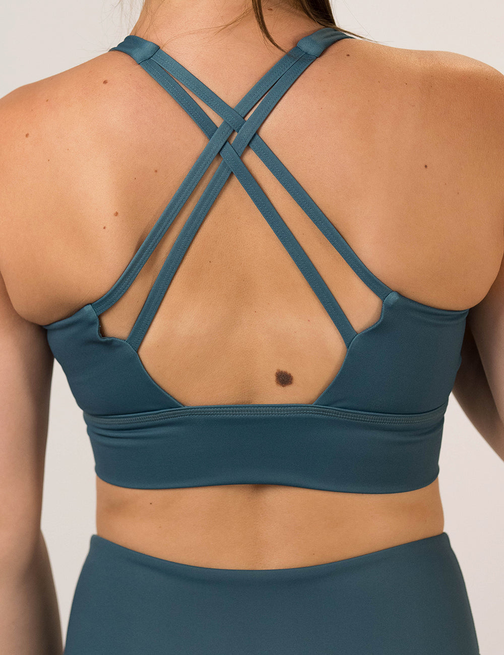 back of the Teal sports bra with black leaf pattern on a white background