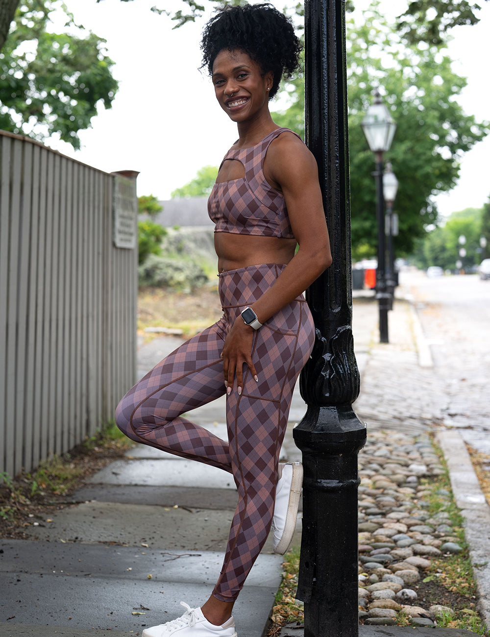 model wearing the grey, beige, and dark red plaid full length leggings and bra outside