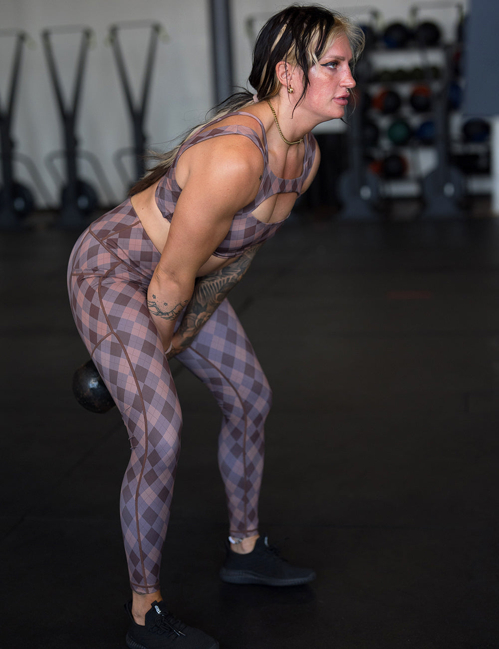 model wearing the grey, beige, and dark red plaid full length legging working out in the gym