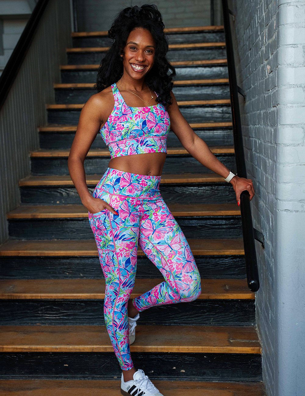 model wearing the colorful butterfly and flowers leggings and bra posing in a stairwell