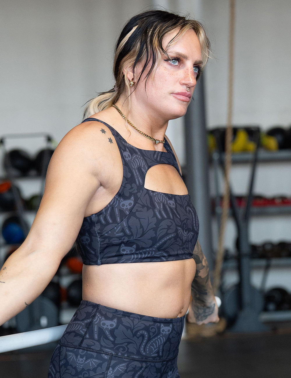 model wearing the black and grey bats and cats skeleton sports bra working out in the gym